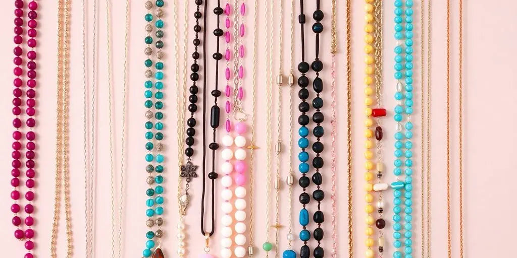 Various long necklaces displayed on a neutral background.