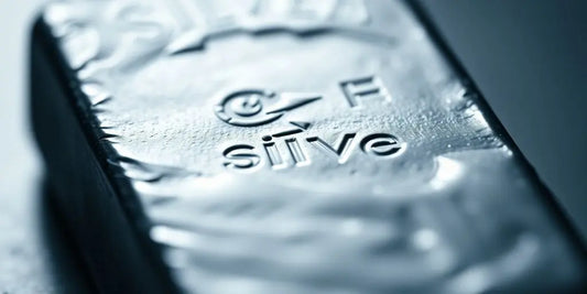 Close-up of a shiny silver ingot on a blurred background.