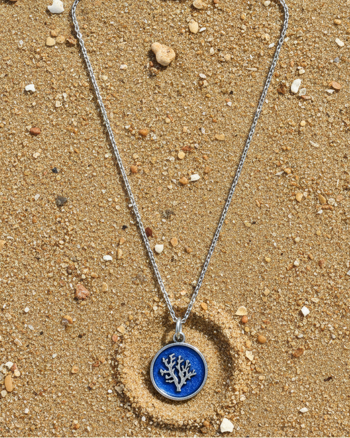 Necklace with a blue pendant on a sandy surface